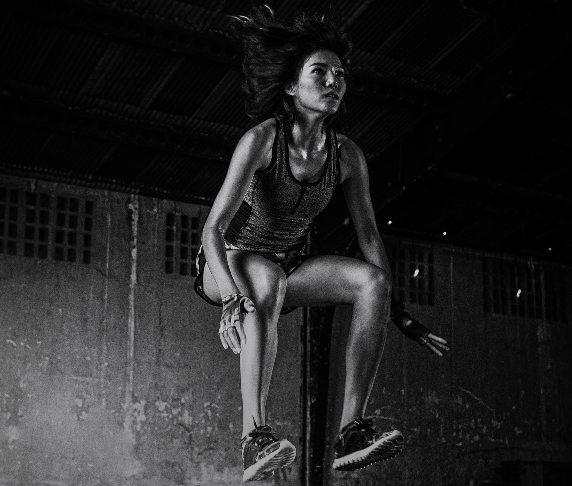 Imagen en blanco y negro de una chica asiática con ropa deportiva saltando.